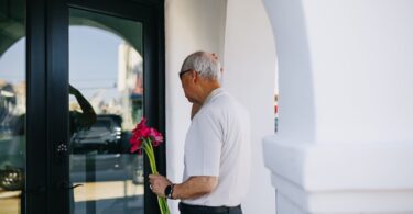 man in white polo shirt holding bouquet of flowers