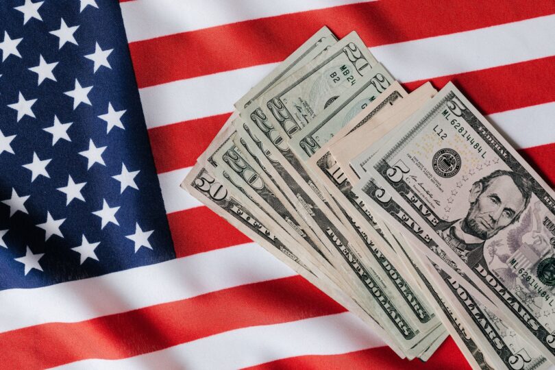 united states flag and pile of dollar bills
