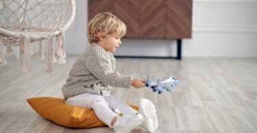 boy in gray sweater holding toy plane