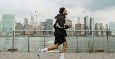man wearing jacket and black shorts running in the city