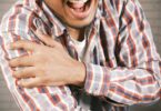 close up photo of an aching man holding his shoulder